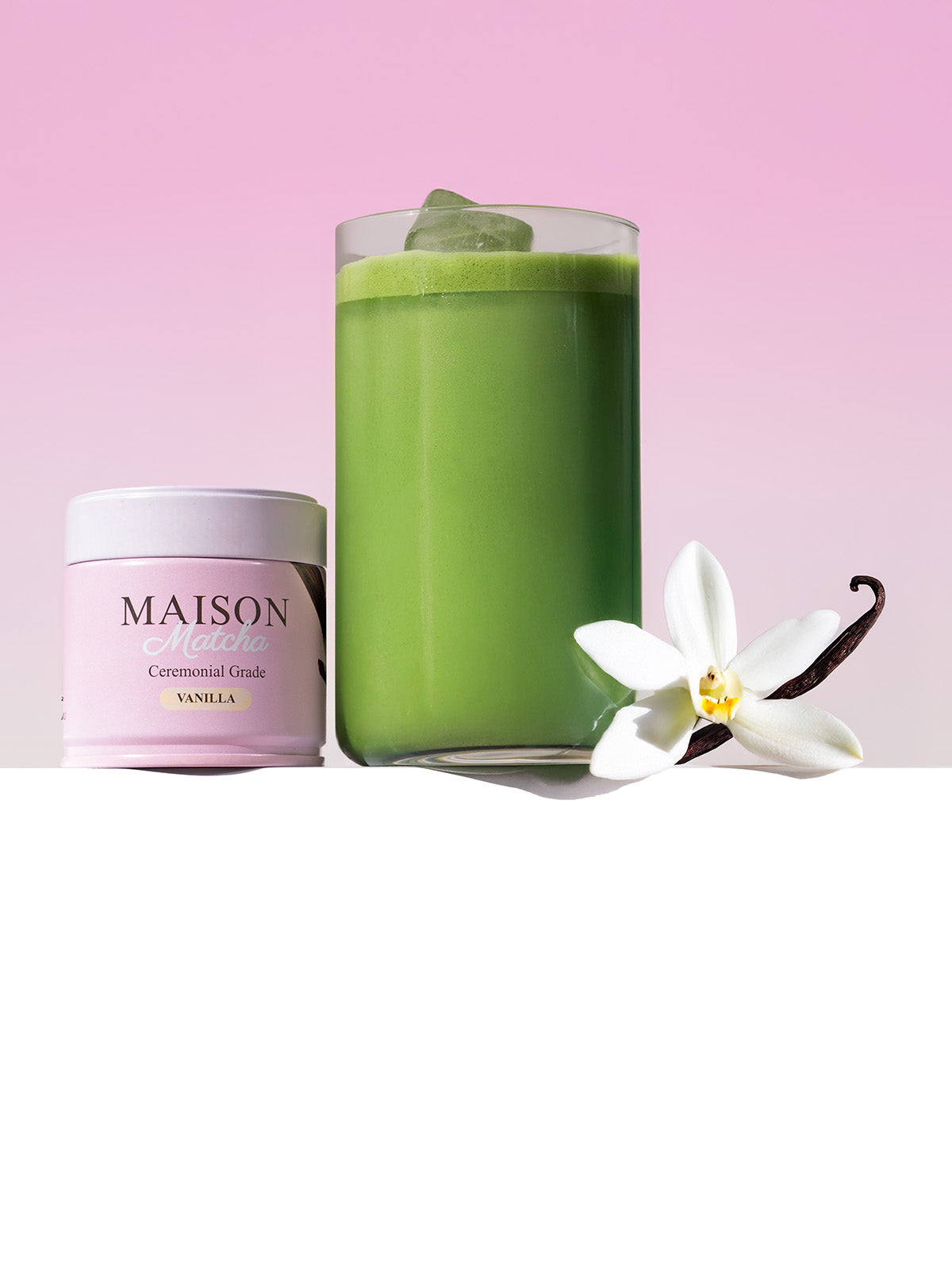 Maison Matcha Ceremonial Vanilla Matcha can beside iced vanilla matcha latte with vanilla bean and flower