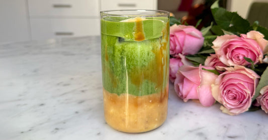 Banana caramel matcha latte on a table with pink roses behind