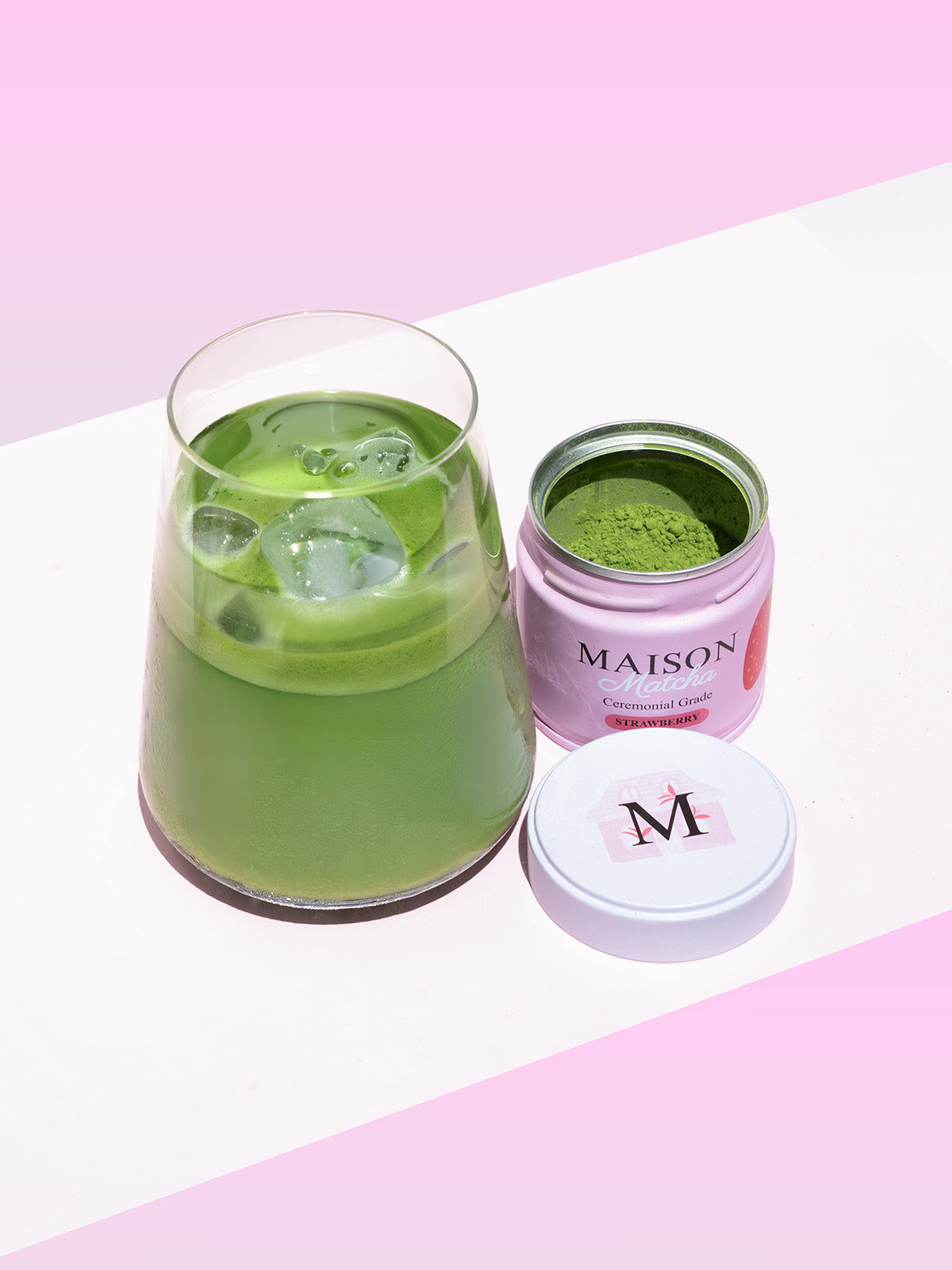 Iced matcha latte next to Maison Matcha strawberry can open with fresh matcha powder