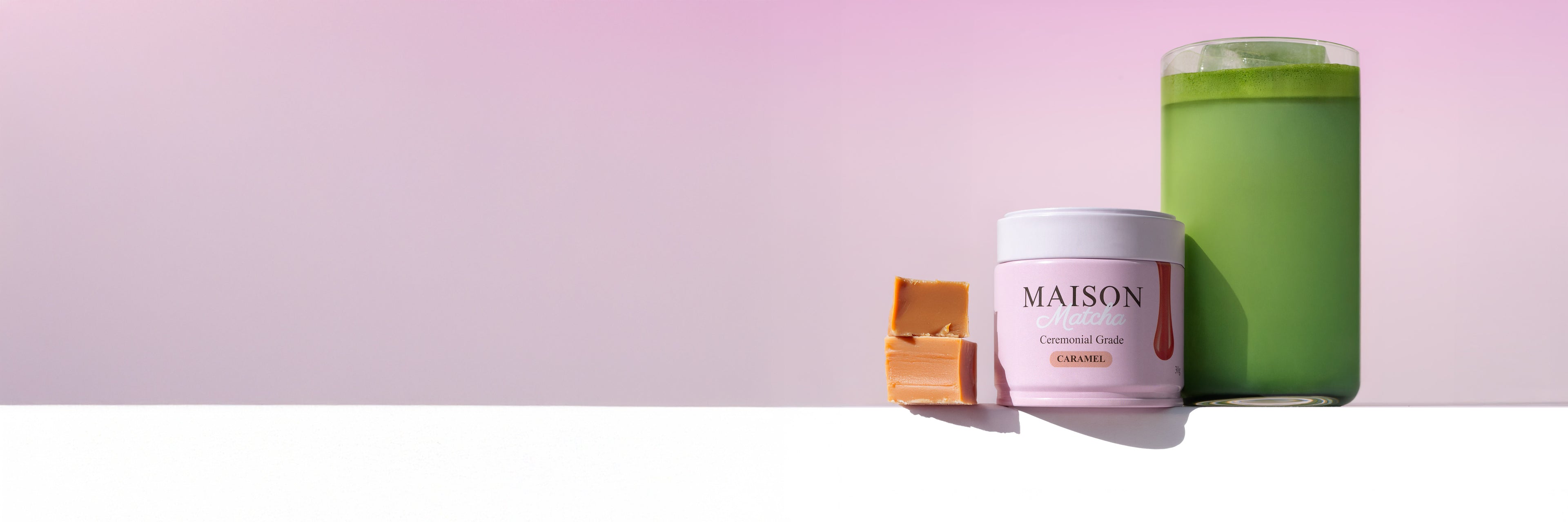 Maison matcha caramel matcha powder can next to caramel bites and an iced matcha latte