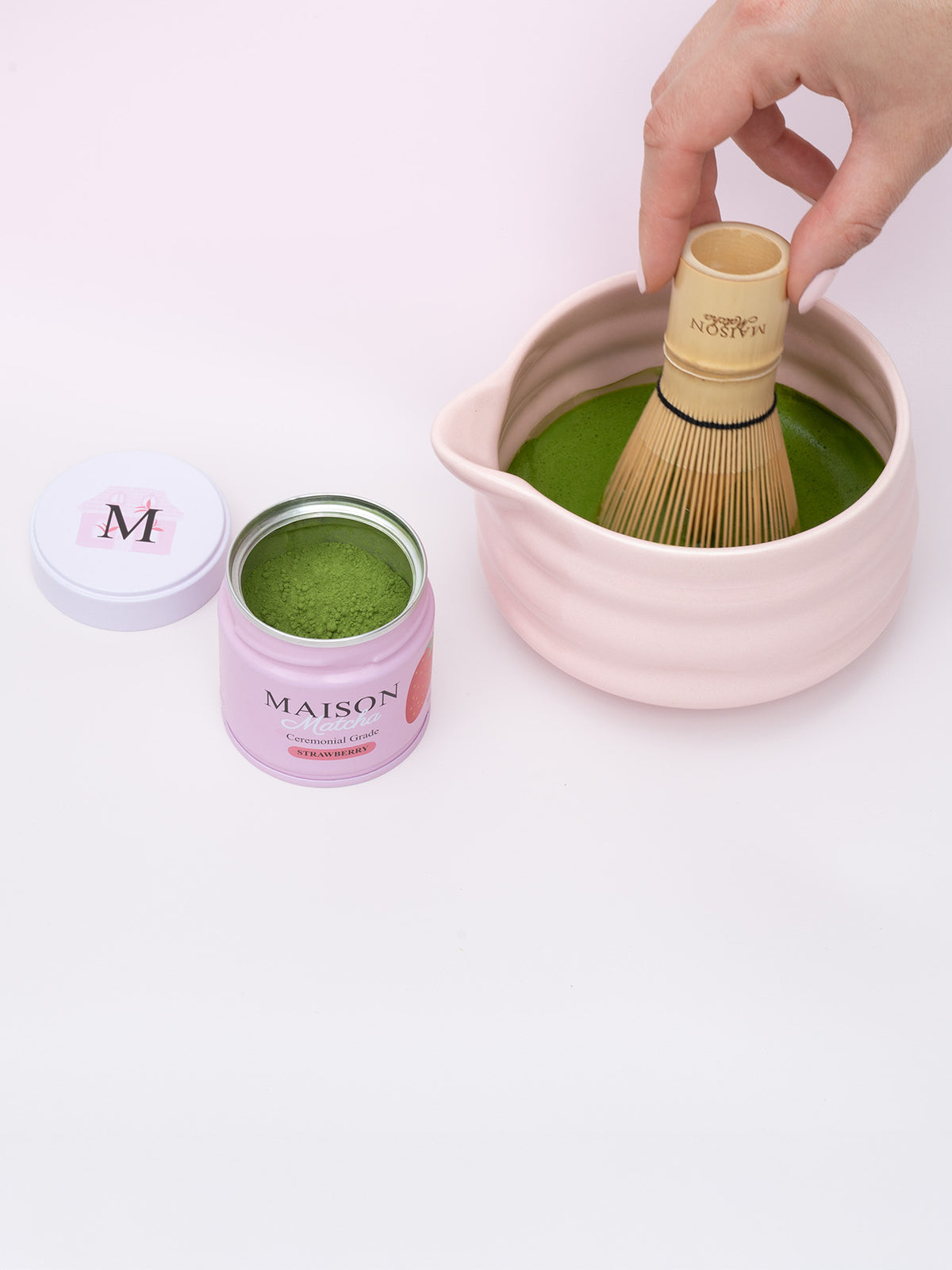 Maison Matcha strawberry can opened with fresh powder, next to matcha bowl and bamboo whisk