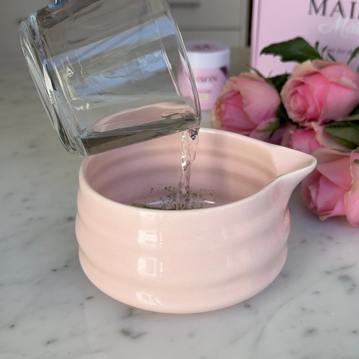 Water being poured into a pink matcha bowl