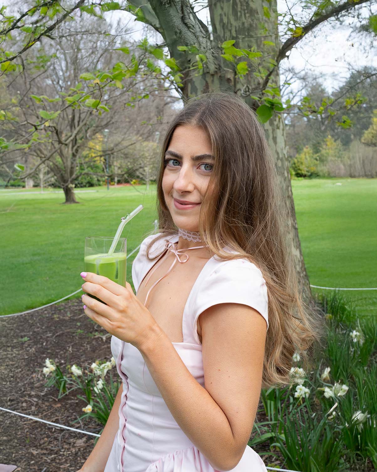 Portrait of Cassandra Durand, founder of Maison Matcha, smiling in a sunny park, holding vibrant green matcha latte.