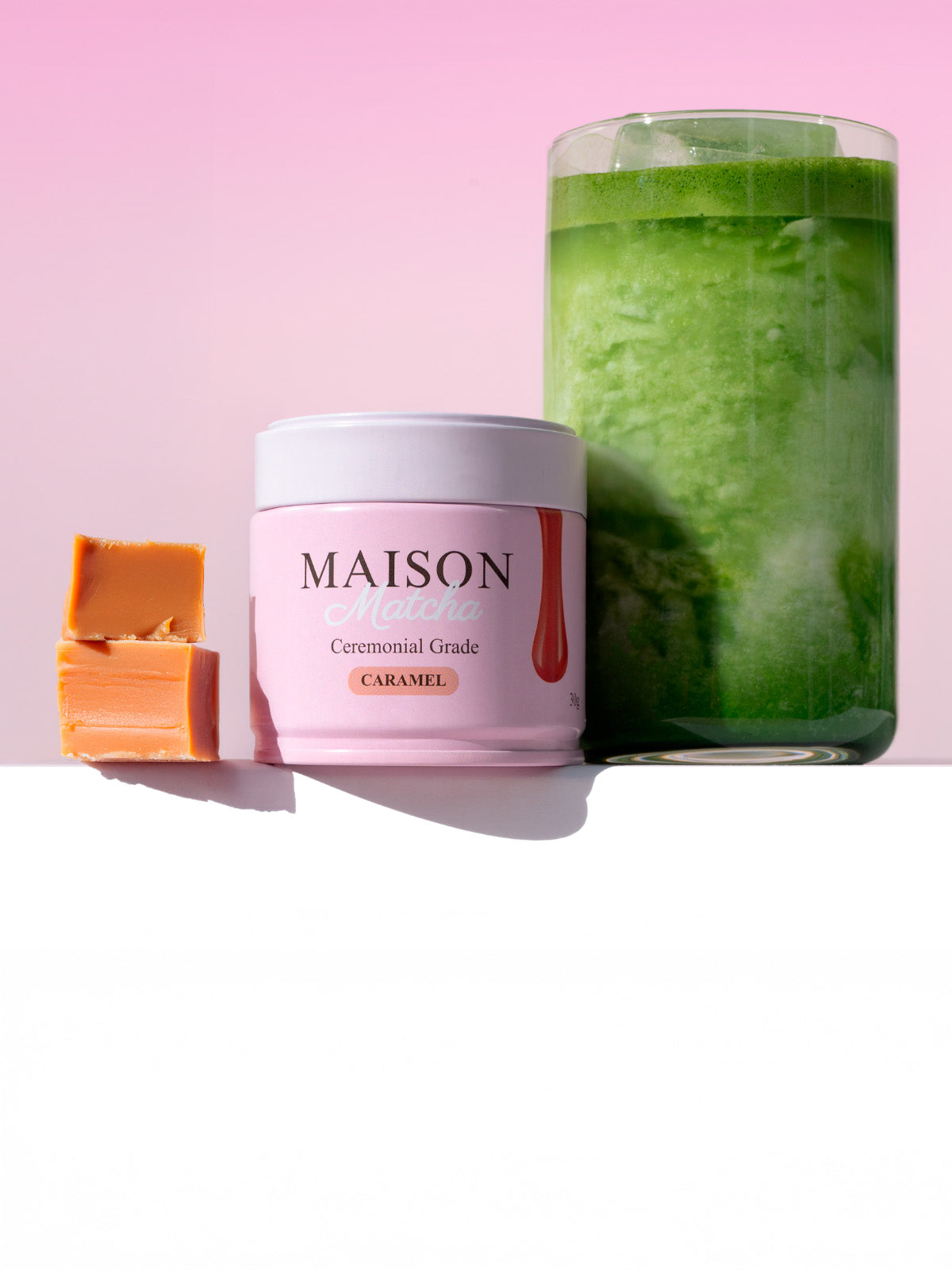 Maison Matcha Ceremonial Caramel Matcha can next to iced matcha latte and two caramel bites