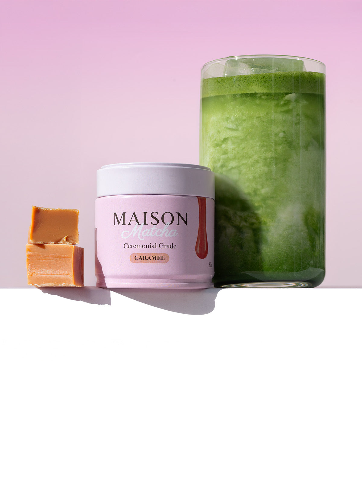 Maison Matcha Ceremonial Caramel Matcha can next to iced matcha latte and two caramel bites
