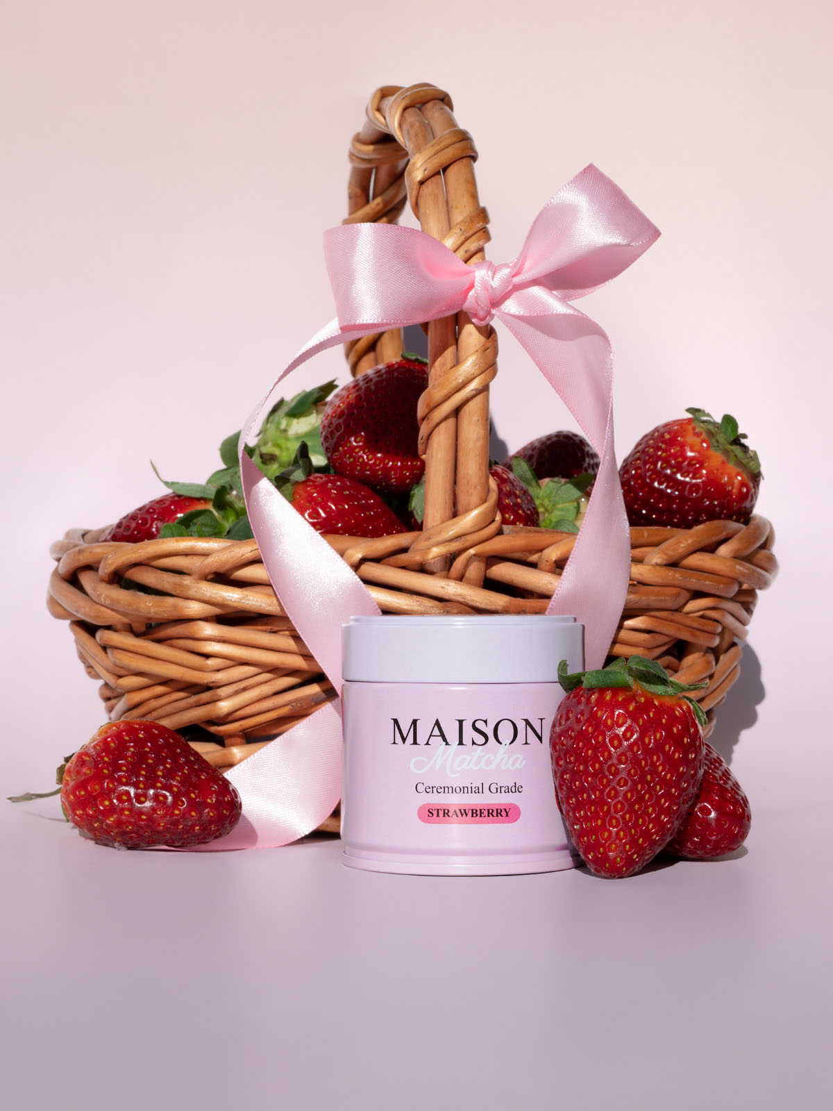 Maison Matcha Ceremonial Strawberry Matcha can in front of a basket of fresh strawberries with a pink ribbon