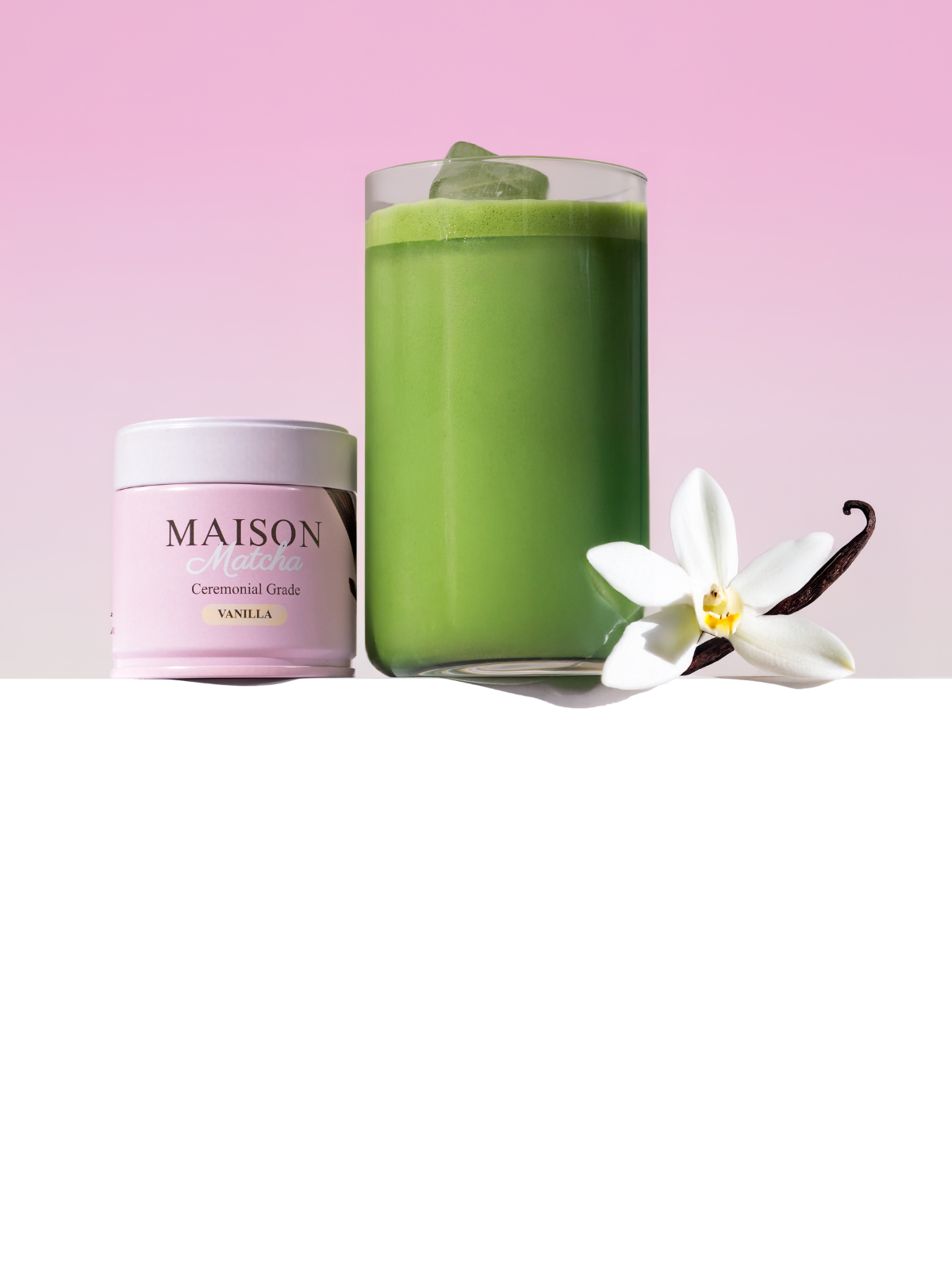 Maison Matcha Ceremonial Vanilla Matcha can next to iced matcha latte with vanilla bean and flower