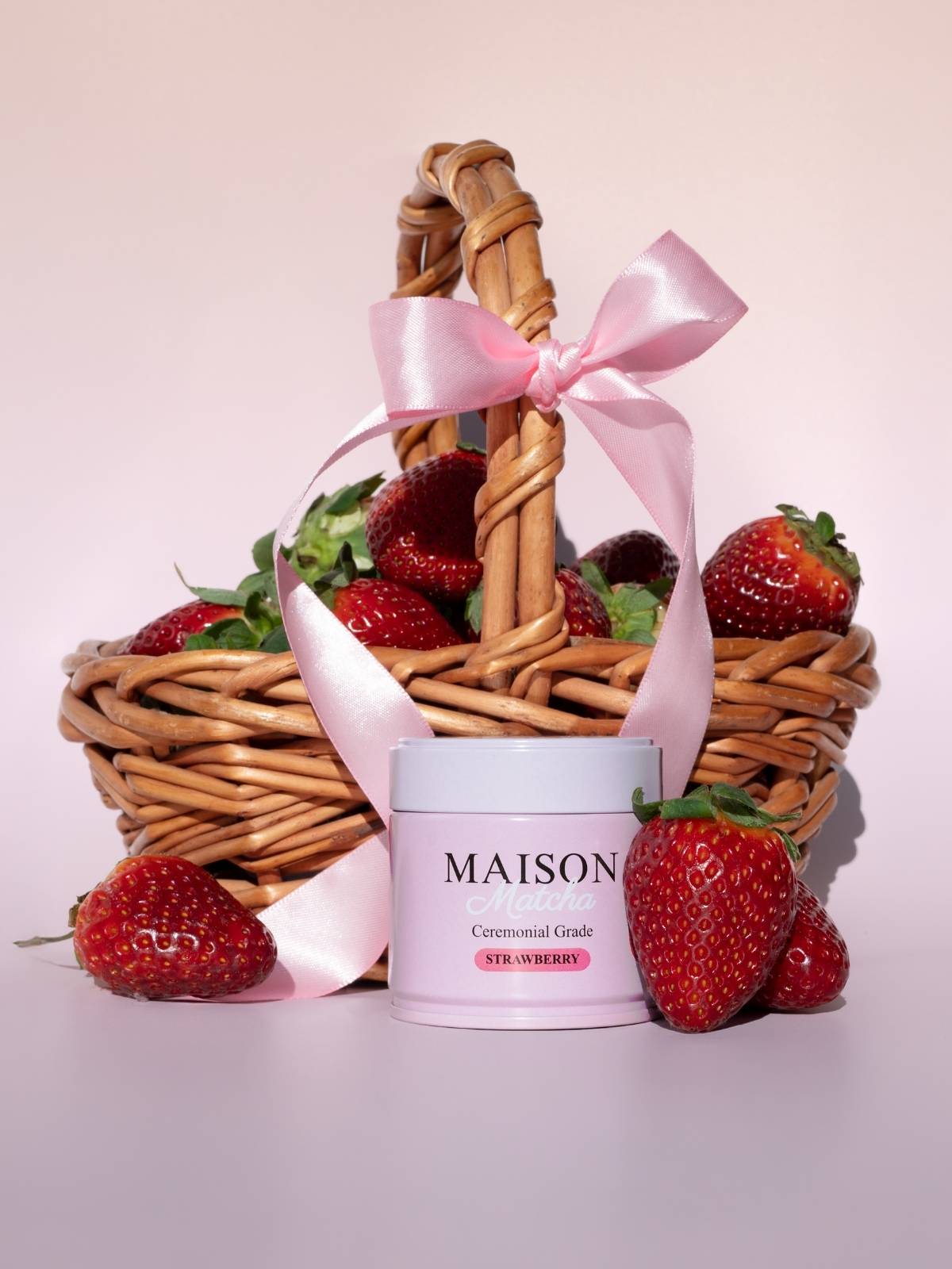 Strawberry ceremonial matcha powder can with basket of fresh strawberries and pink ribbon